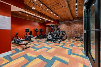 A gym with a variety of exercise equipment and a colorful floor